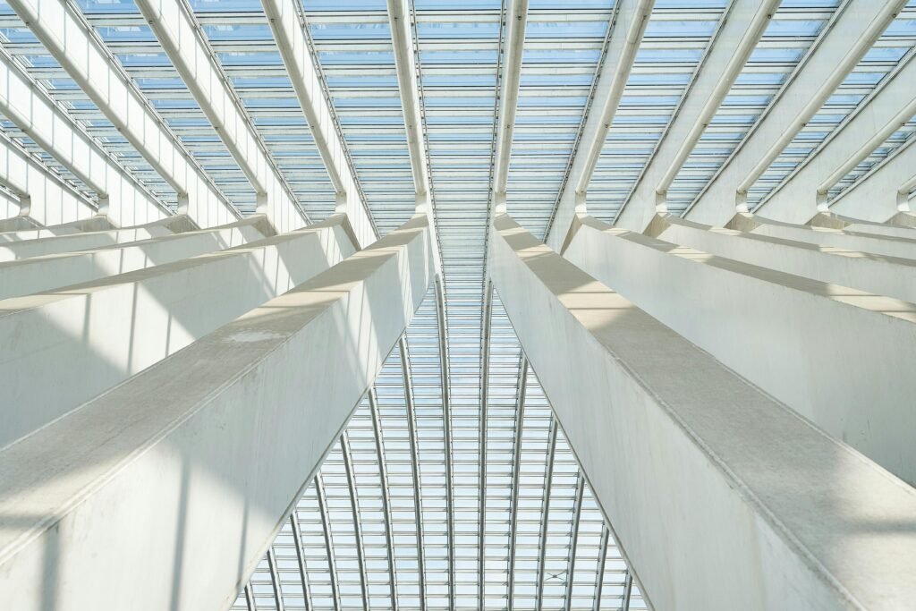 A striking upward view of a modern ceiling structure featuring geometric beams and glass panels.
